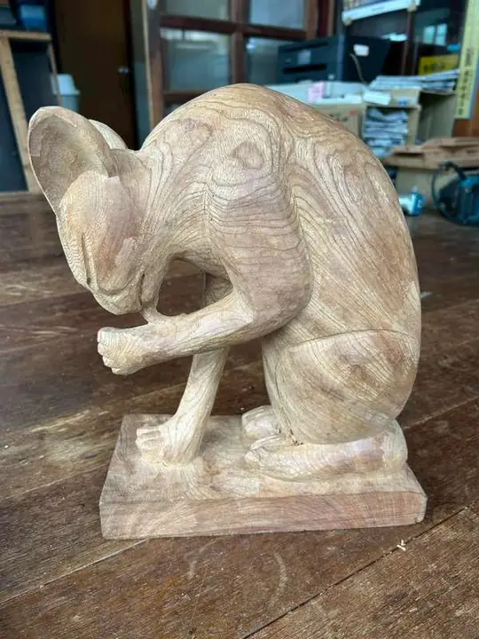 A rat carved in the round, grooming